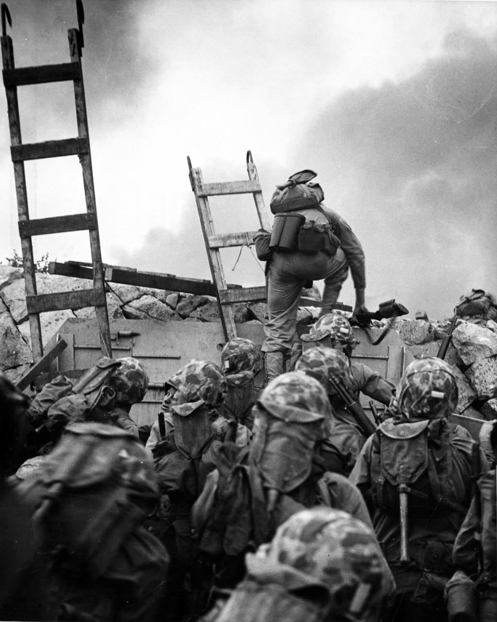 First Lieutenant Baldomero Lopez, USMC, leads the 3rd Platoon, Company A, 1st Battalion, 5th Marines over the seawall on the northern side of Red Beach, as the second assault wave lands, 15 September 1950. Wooden scaling ladders are in use to facilitate disembarkation from the LCVP that brought these men to the shore. Lt. Lopez was killed in action within a few minutes, while assaulting a North Korean bunker. U.S. Marine Corps Photograph, from the collections of the Naval History and Heritage Command.