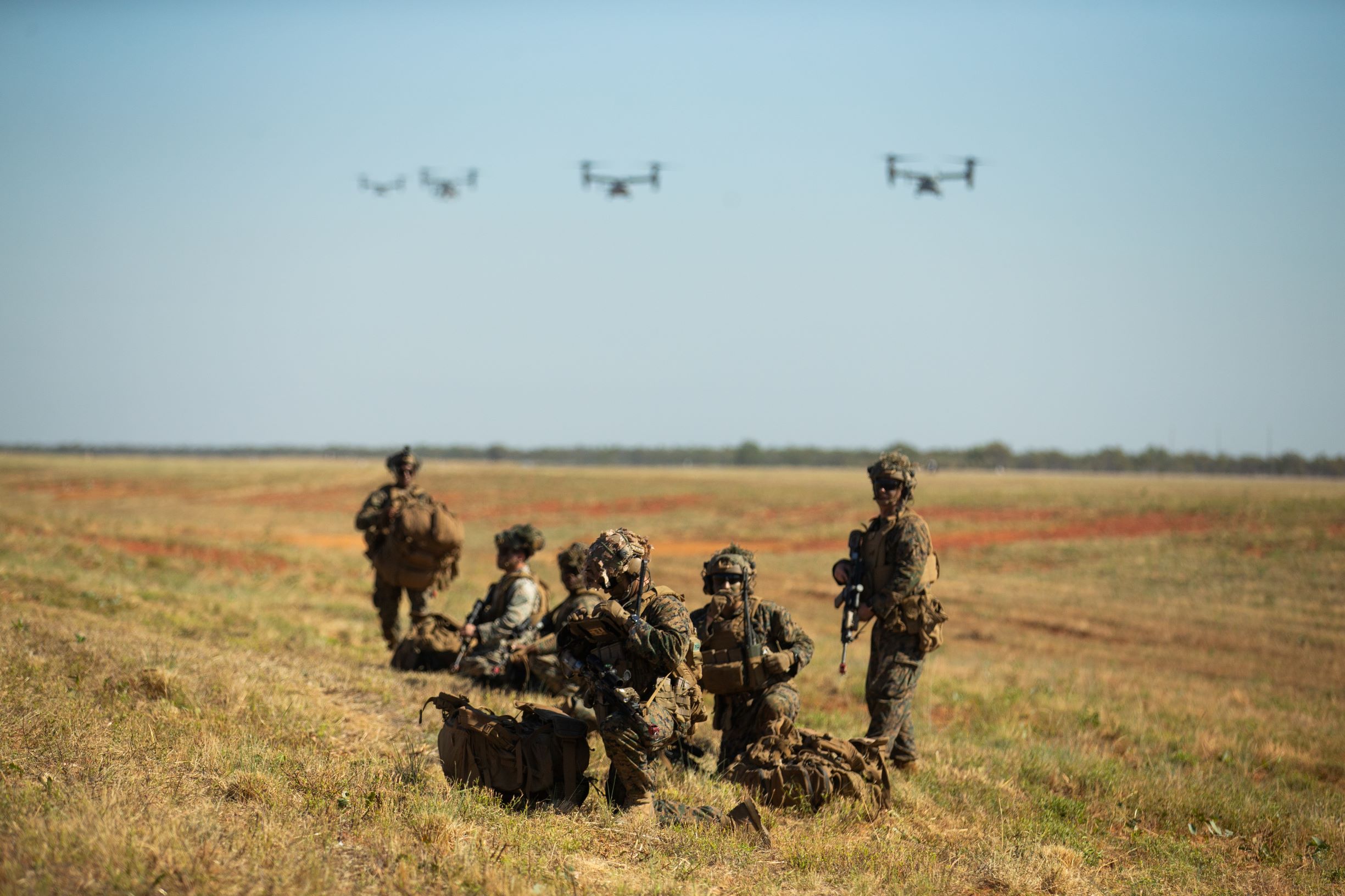U.S. Marines with 3d Battalion, 7th Marine Regiment, Ground Combat Element, Marine Rotational Force-Darwin 22, establish defensive positions as MV-22 Ospreys approach for landing during an airfield seizure event as part of exercise Koolendong 22 at Royal Australian Air Force Base Curtin, WA, Australia, July 18, 2022. Exercise Koolendong 22 is a combined and joint force exercise focused on expeditionary advanced base operations conducted by U.S. Marines, U.S. Soldiers, U.S. Airmen, and Australian Defence Force personnel. (U.S. Marine Corps photo by Cpl. Cedar Barnes)