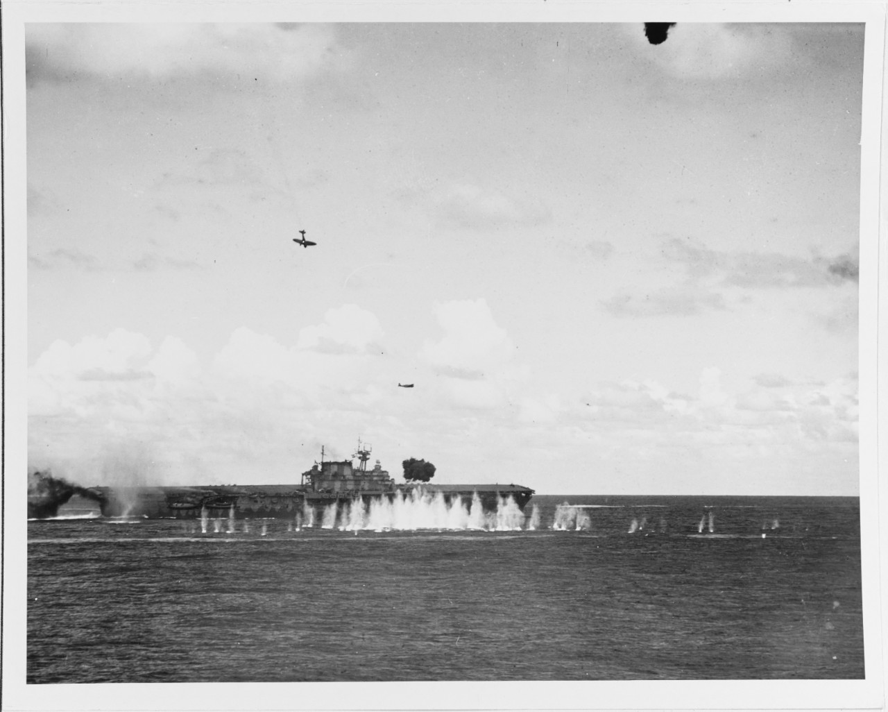 A Japanese Type 99 shipboard bomber (Allied codename Val) trails smoke as it dives toward USS Hornet (CV-8), during the morning of 26 October 1942. This plane struck the ship's stack and then her flight deck. A Type 97 shipboard attack plane (Kate) is flying over Hornet after dropping its torpedo, and another Val is off her bow. Note anti-aircraft shell burst between Hornet and the camera, with its fragments striking the water nearby. Official U.S. Navy Photograph, now in the collections of the U.S. National Archives.